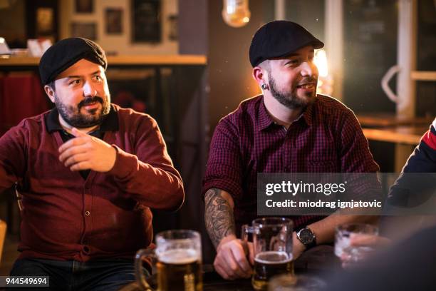 group of men drinking beer in a bar - hooligan stock pictures, royalty-free photos & images