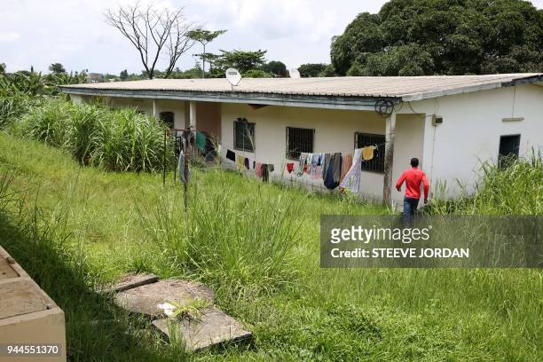 Student of the Institut Africain d'informatique walks towards one of the buildings amid high grass and laundry lines on the campus in Libreville on...