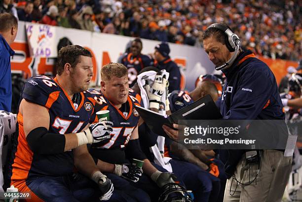 Offensive line coach Rick Dennison and Chris Kuper and Tyler Polumbus of the Denver Broncos look over photos in the bench area during their NFL game...