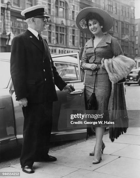 English pop singer Alma Cogan leaves her home in Kensington, London, for Royal Ascot, wearing a bamboo picture hat and a mink stole, 19th June 1956.