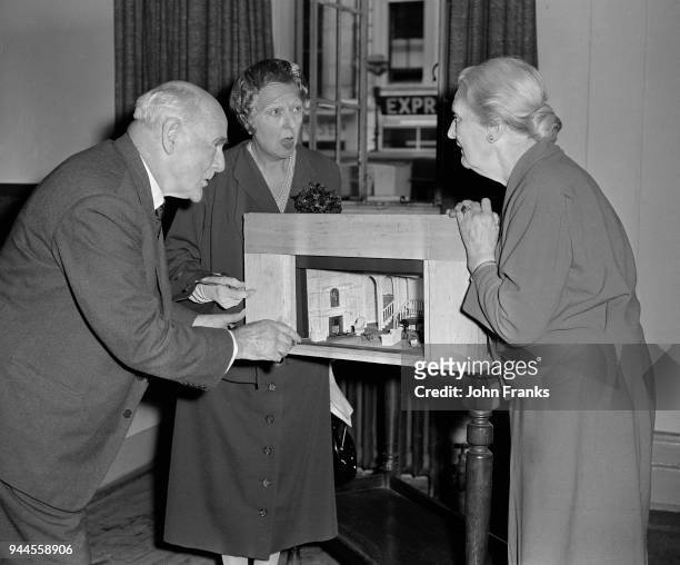 From left to right, actors Lewis Casson , Marie Lohr and Sybil Thorndike discuss a model of the set for the Noël Coward play 'Waiting In The Wings'...