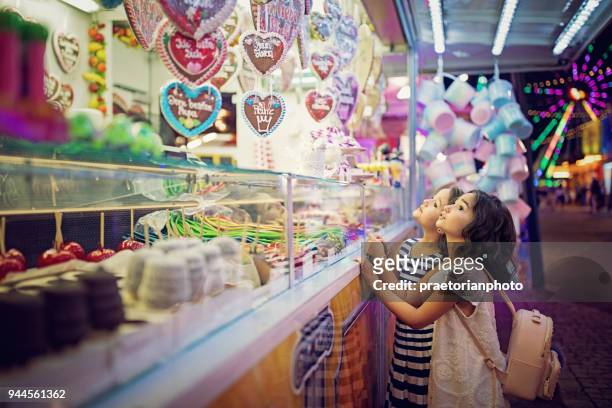 zwei kleine mädchen suchen süßigkeiten in den süßigkeiten-wagen auf der kirmes - kirmes fahrgeschäft stock-fotos und bilder