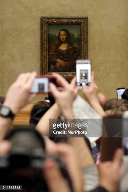 Visitors take pictures of 'La Joconde', a 1503-1506 oil on wood portrait of Mona Lisa by Leonardo Da Vinci, at the Louvre Museum in Paris, on April...