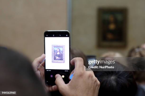 Visitor takes a picture of 'La Joconde', a 1503-1506 oil on wood portrait of Mona Lisa by Leonardo Da Vinci, at the Louvre Museum in Paris, on April...