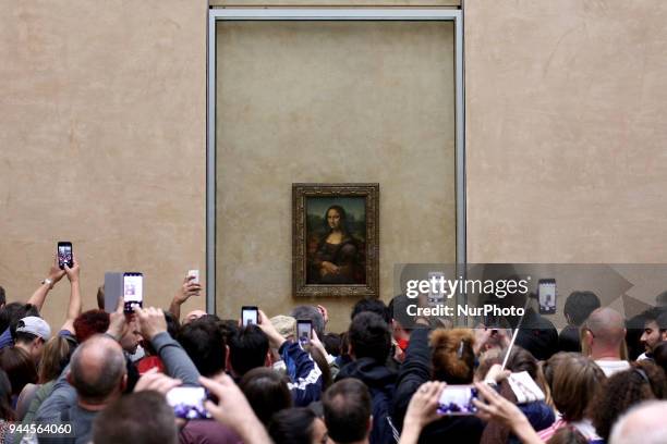 Visitors take pictures of 'La Joconde', a 1503-1506 oil on wood portrait of Mona Lisa by Leonardo Da Vinci, at the Louvre Museum in Paris, on April...