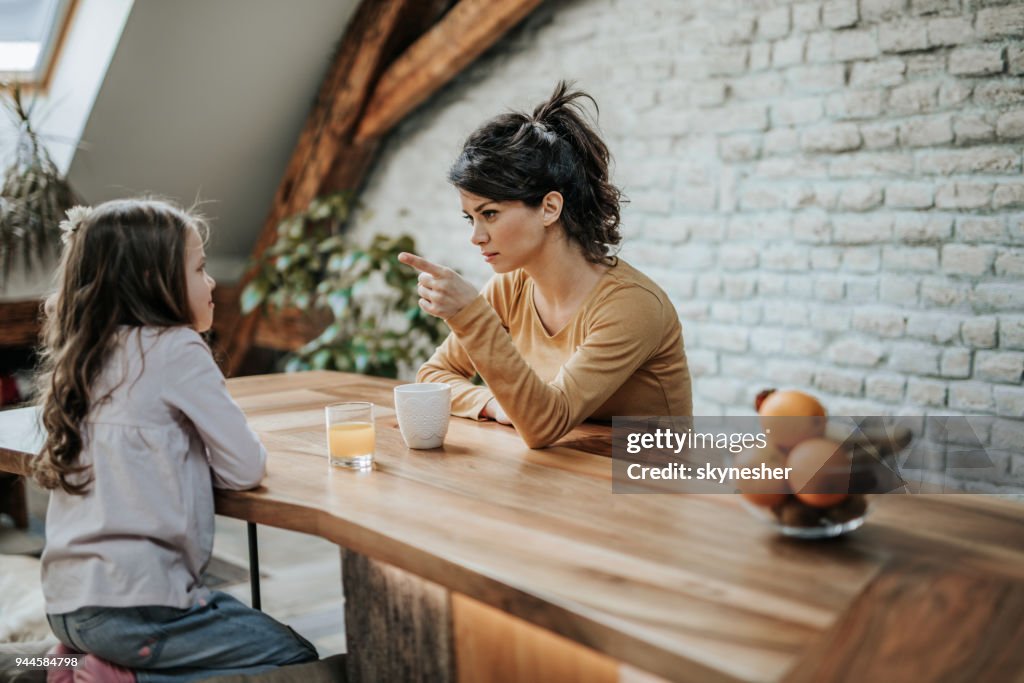 Young mother scolding her little daughter at home.