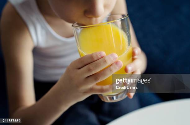 little boy drinking orange juice - drinking juice stock-fotos und bilder