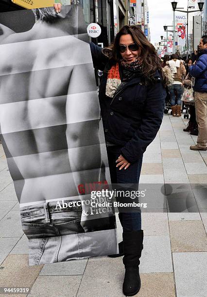 Shopper poses with a promotional poster at the opening of the first Abercrombie & Fitch Co. Shop in Tokyo, Japan, on Tuesday, Dec. 15, 2009....
