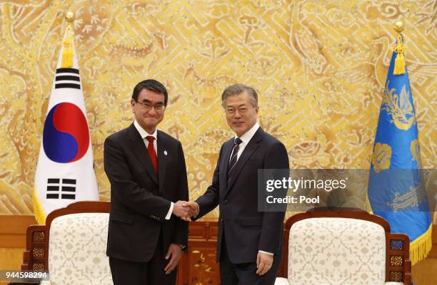 South Korean President Moon Jae-In shakes hands with Japanese Foreign Minister Taro Kono during their meeting at the presidential blue house on April...