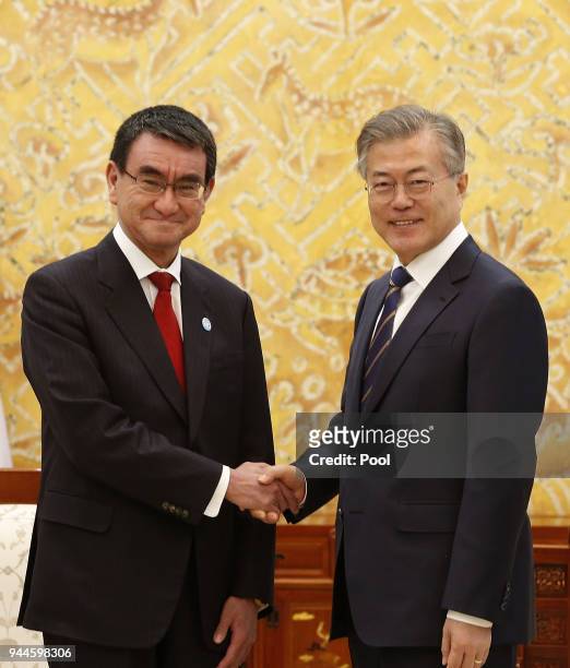 South Korean President Moon Jae-In shakes hands with Japanese Foreign Minister Taro Kono during their meeting at the presidential blue house on April...