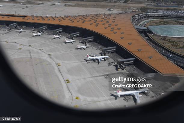 This aerial view taken through the window of a plane, shows various Airbus A330 and Boeing 737 planes of Air China parked at the gates of terminal 3...