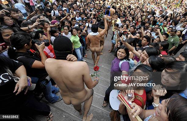 Nude members of the a university fraternity make their way through a crowd of students during the traditional 'Oblation Run' at the University of the...