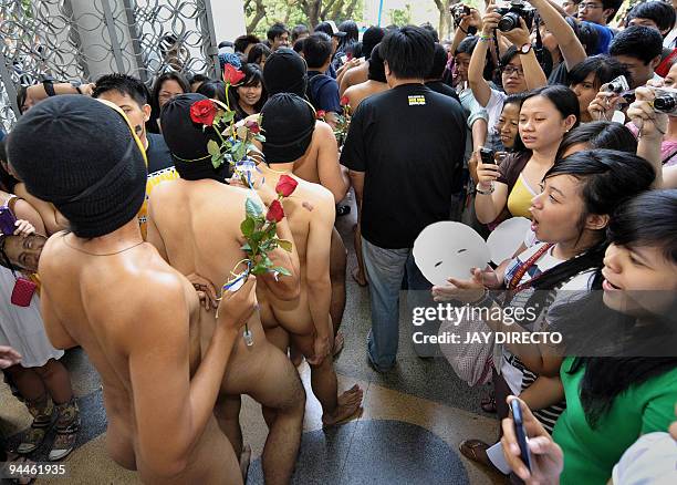 Nude members of the a university fraternity make their way through a crowd of students during the traditional 'Oblation Run' at the University of the...