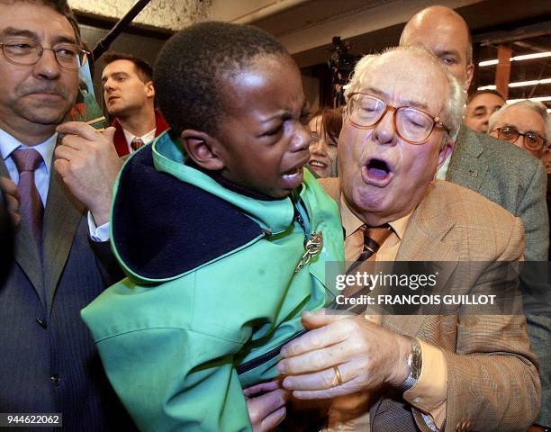 Le président du Front National et candidat à l'élection présidentielle, Jean-Marie Le Pen , tient un enfant dans ses bras, le 26 février 2002 porte...