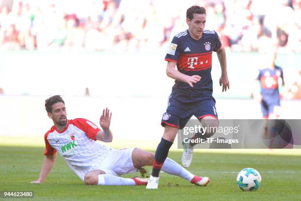 Rani Khedira of Augsburg and Sebastian Rudy of Muenchen battle for the ball during the Bundesliga match between FC Augsburg and FC Bayern Muenchen at...