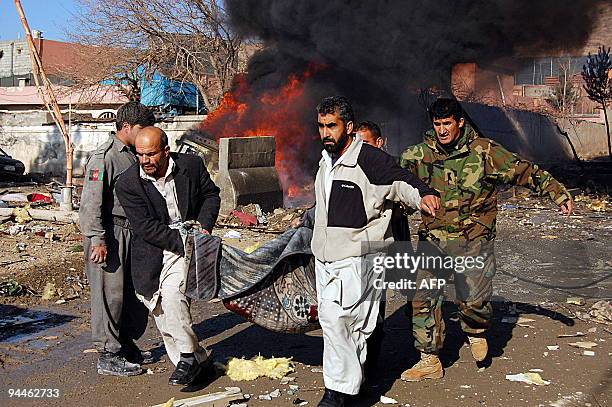 Afghan security personnel use a carpet to carry a victim of a explosion in Kabul on December 15, 2009. A loud explosion rocked the Afghan capital...