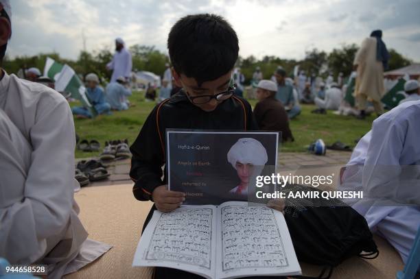 Pakistani religious student reads the Koran as he holds a placard during a demonstration against the April 2 Afghan airstrike in the northeastern...