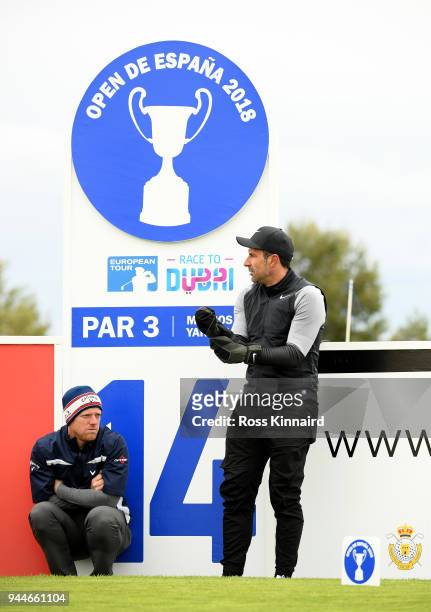 David Horsey of England and former footballer Luís Figo shelter from the wind during the pro-am event prior to the Open de Espana at Centro Nacional...
