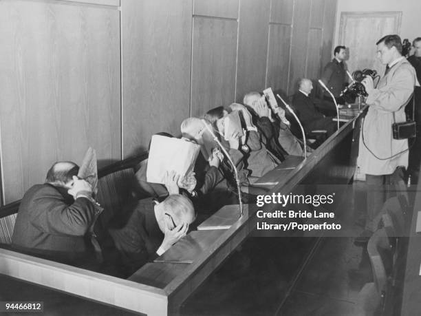 The ten defendants in the 'Treblinka Trial' for Nazi war crimes hide their faces from photographers and cameraman as they await the start of legal...