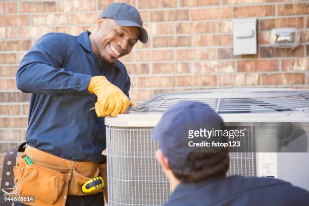 multi-ethnic team of blue collar air conditioner repairmen at work. - repairing stock pictures, royalty-free photos & images