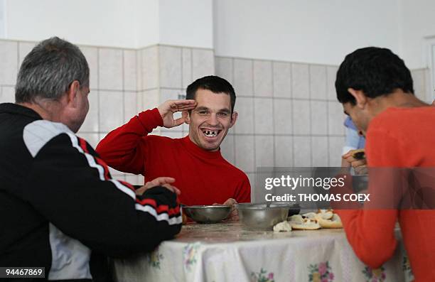 Disabled and orphaned Romanian adults have lunch at the Targu Jiu orphanage refectory on November 25 southwestern Romania, after being transfered...