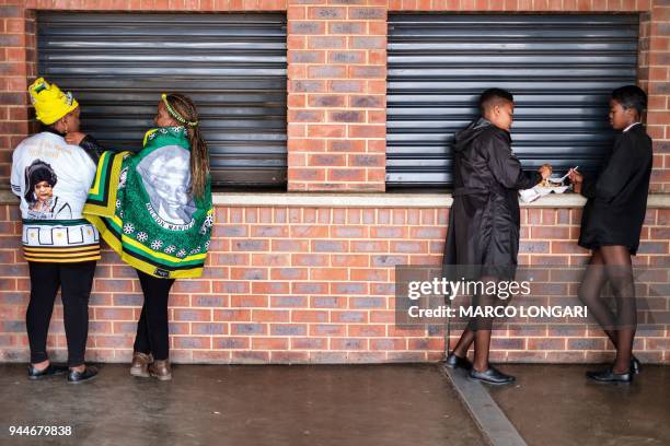 Tow schoolgirls have a snack as two women wearing African National Congress regalia pause at the Orlando stadium in Soweto, Johannesburg, on April...