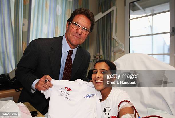 England Manager Fabio Capello signs a shirt for 15 year old Imaan during a Christmas visit to Great Ormond Street Hospital on December 15, 2009 in...