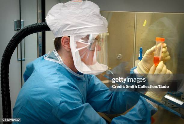 Centers for Disease Control scientist in a protective air-tight suit handling Influenza A Virus specimens, Biosafety Level-4 laboratory, Atlanta,...
