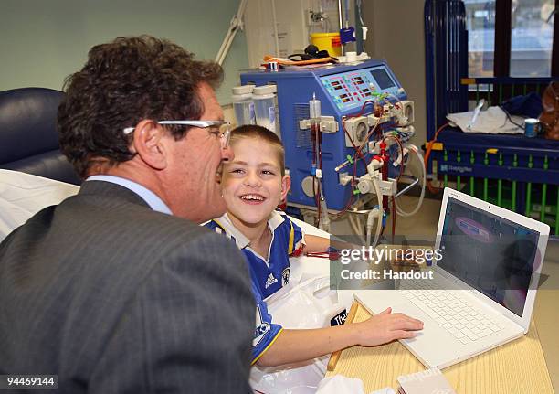 England Manager Fabio Capello signs a shirt for 12 year old Ciaran during a Christmas visit to Great Ormond Street Hospital on December 15, 2009 in...