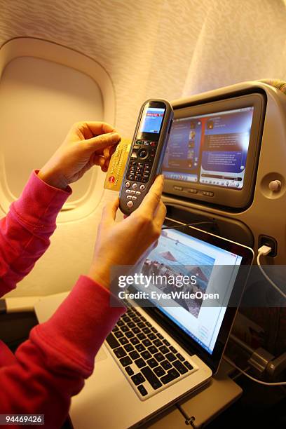 Woman is working with a notebook and makes a telephone call, paid by credit card on board of a Emirates Airline passenger jet on December 08, 2009 in...