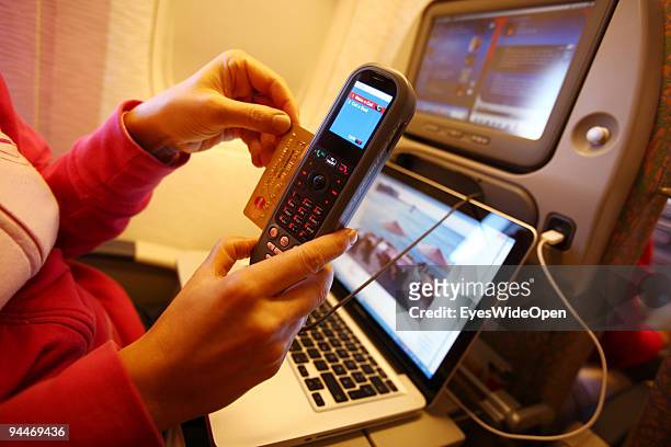 Woman is working with a notebook and makes a telephone call, paid by credit card on board of a Emirates Airline passenger jet on December 08, 2009 in...