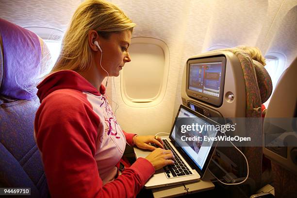 Woman is working with a notebook and listen to music with headphones on board of a Emirates Airline passenger jet on December 08, 2009 in Trivandrum,...
