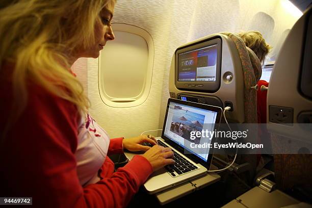 Woman is working with a notebook and listen to music with headphones on board of a Emirates Airline passenger jet on December 08, 2009 in Trivandrum,...