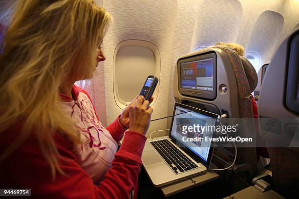 Woman is working with a notebook and makes a telephone call on board of a Emirates Airline passenger jet on December 08, 2009 in Trivandrum, India....