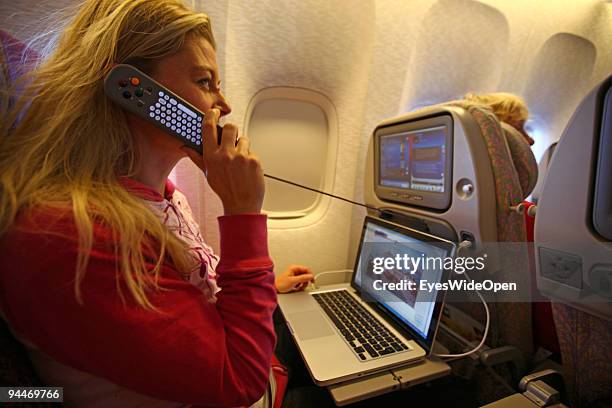 Woman is working with a notebook and makes a telephone call on board of a Emirates Airline passenger jet on December 08, 2009 in Trivandrum, India....