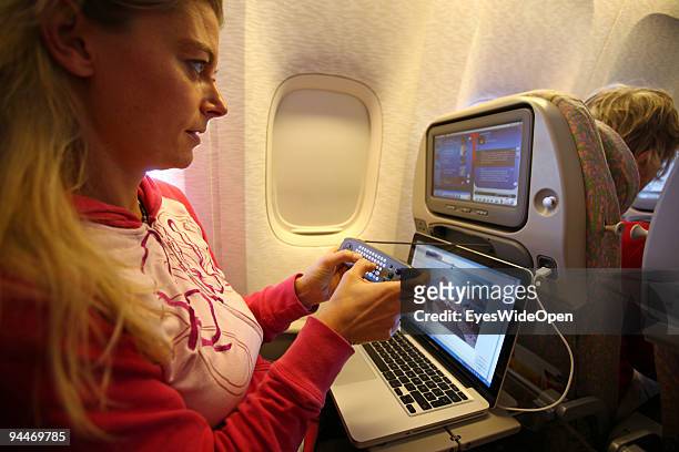 Woman is working with a notebook and makes a telephone call on board of a Emirates Airline passenger jet on December 08, 2009 in Trivandrum, India....