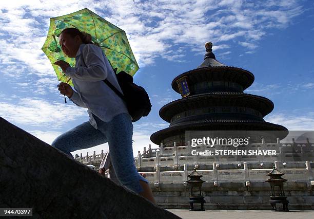 Chinese tourist fights the scorching sun and heat with an umbrella as she visits Beijing's Temple of Heaven 28 July 2000, which has come to symbolize...