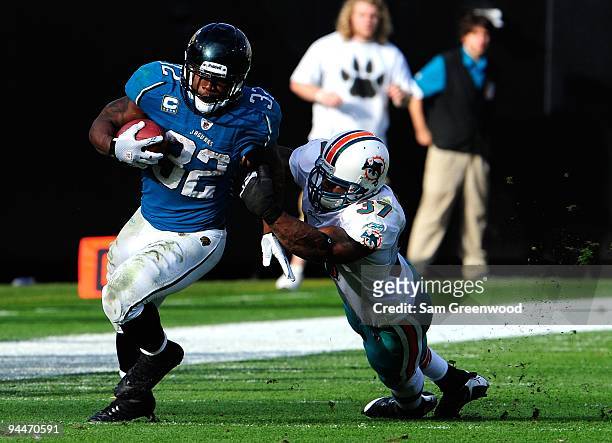 Yeremiah Bell of the Miami Dolphins attempts to tackle Maurice Jones-Drew of the Jacksonville Jaguars during the game at Jacksonville Municipal...