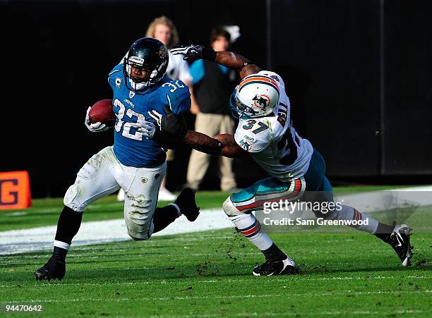 Yeremiah Bell of the Miami Dolphins attempts to tackle Maurice Jones-Drew of the Jacksonville Jaguars during the game at Jacksonville Municipal...