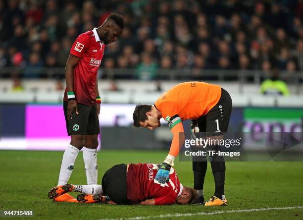 Niclas Fuellkrug of Hannover lays on the ground and Salif Sane of Hannover and Goalkeeper Philipp Tschauner of Hannover look on during the Bundesliga...