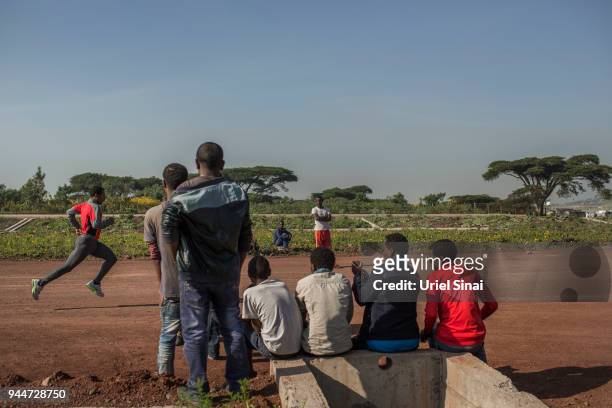 Locals stand by the road and watch Kenenisa Bekele runs during a training at a highway under construction on September 26, 2015. In Kalite, Ethiopia....
