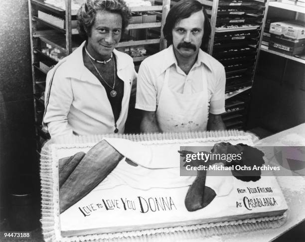 Casablanca Records executive and a baker pose by a cake baked for Donna Summer and presented to her by Casablanca records in 1976.