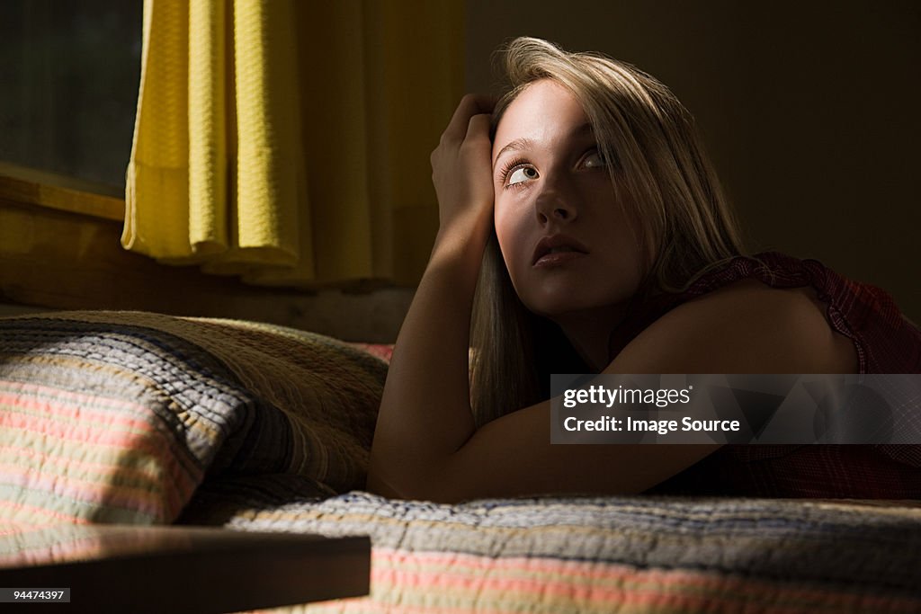 Young woman on bed in shadows