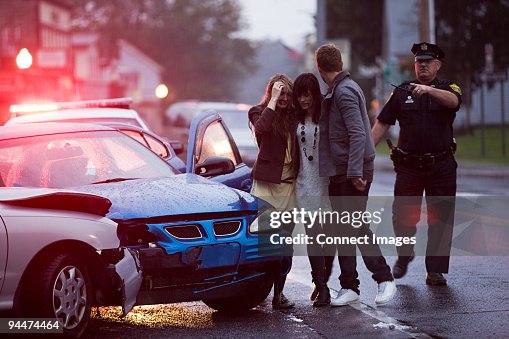 Young people and police officer at scene of car crash Young people and police officer at scene of car crash