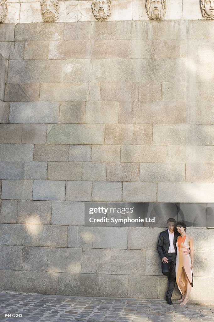 Couple leaning against wall