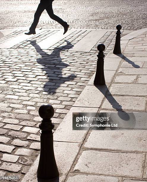 businessman running along crosswalk on cobblestone street - adoquinado fotografías e imágenes de stock
