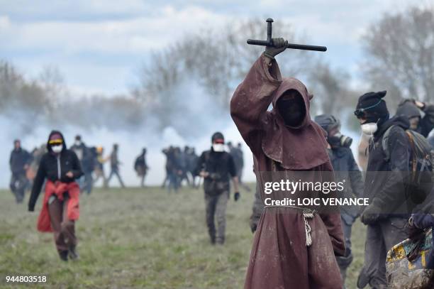 Protester dressed as a monk raises a police baton on April 11 during a police operation to raze the decade-old anti-capitalist camp known as ZAD set...