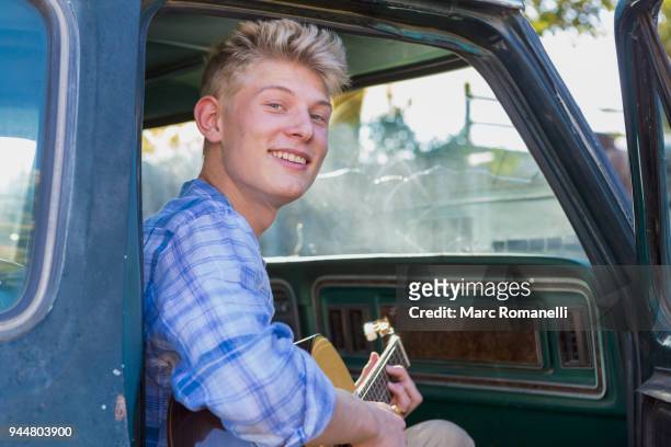 teen boy playing guitar in pick up truck - guitar pick stock pictures, royalty-free photos & images