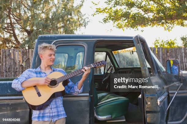 teen boy playing guitar,  leaning on  pick up truck - guitar pick stock pictures, royalty-free photos & images