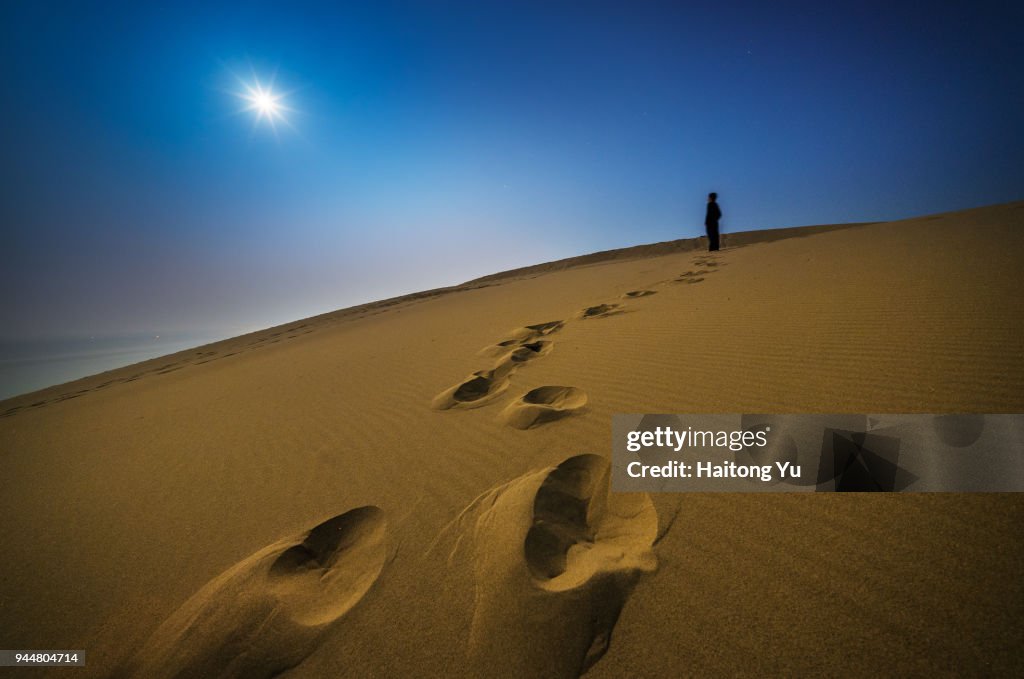 Desert under moonlight with footprints